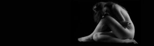 A black and white photo of a naked woman practicing post liposuction leak and care.