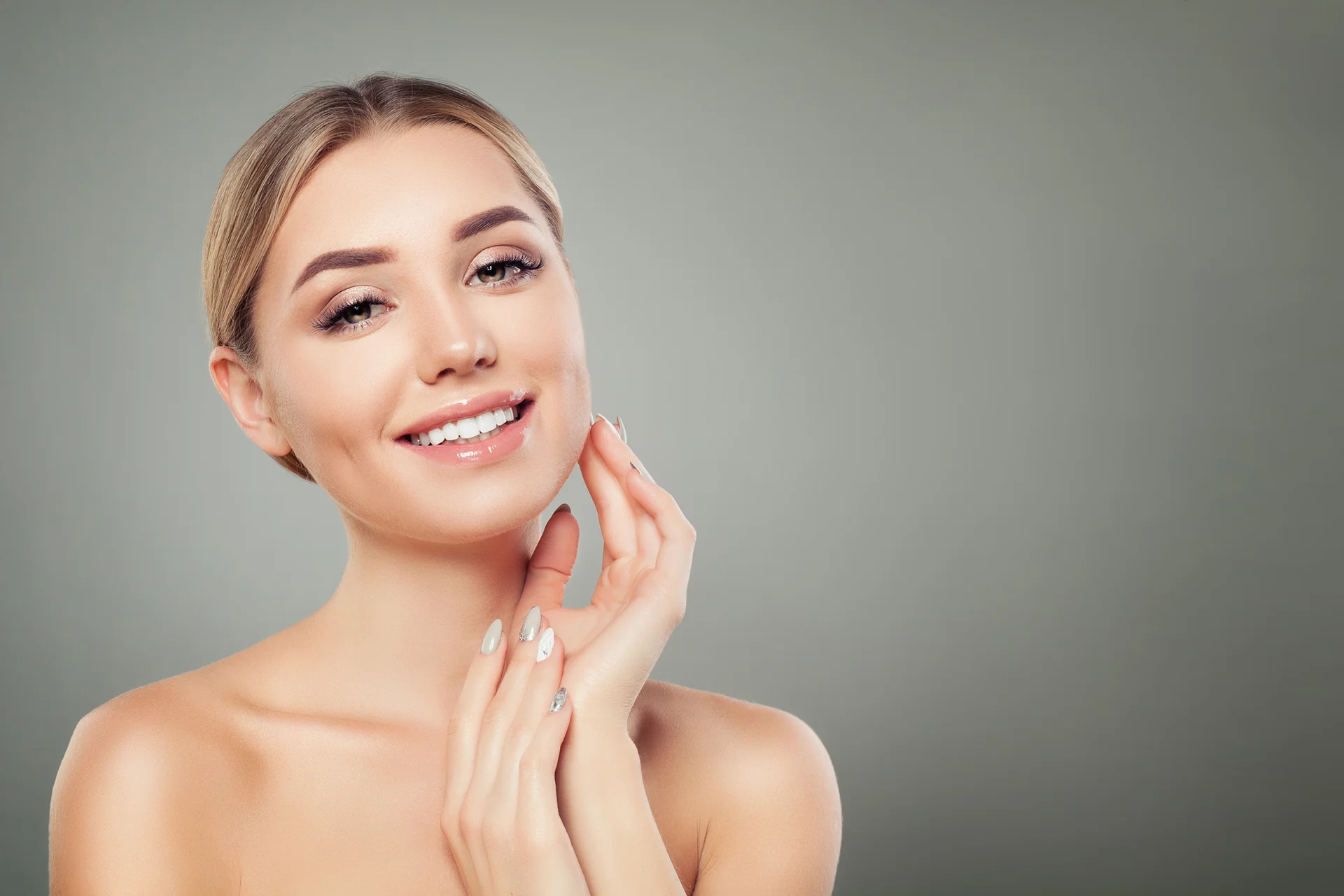 A beautiful woman posing with her hands on her face, showcasing the importance of a compression garment for chin lipo patients.
