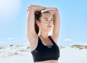 A young woman practicing yoga on the beach, focusing on her arm strength and flexibility