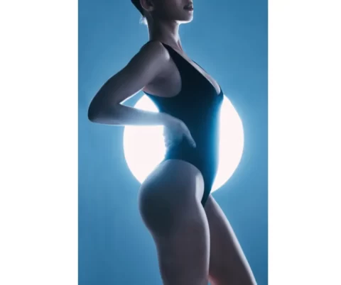 A woman is posing in a black swimsuit, showcasing her toned abdomen.