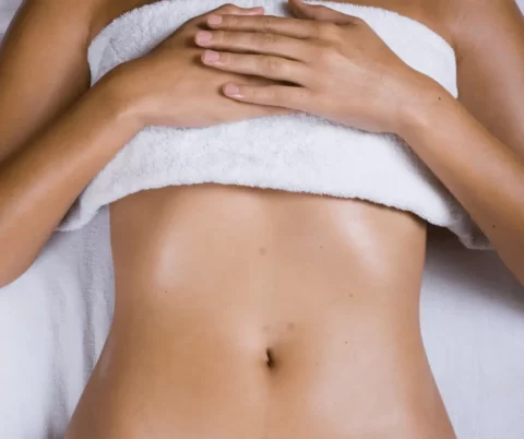 A woman with a towel wrapped around her abdomen.