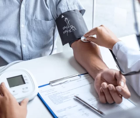 A doctor is checking a patient's blood pressure while examining their abdomen.