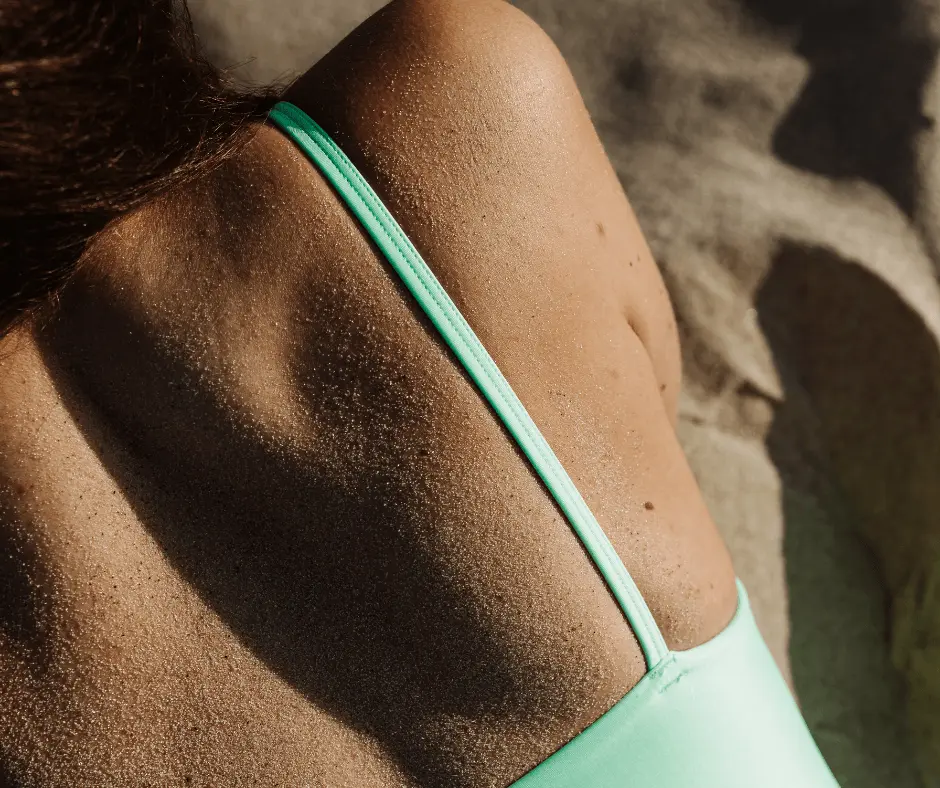 A woman sporting a green bikini that highlights her toned back.