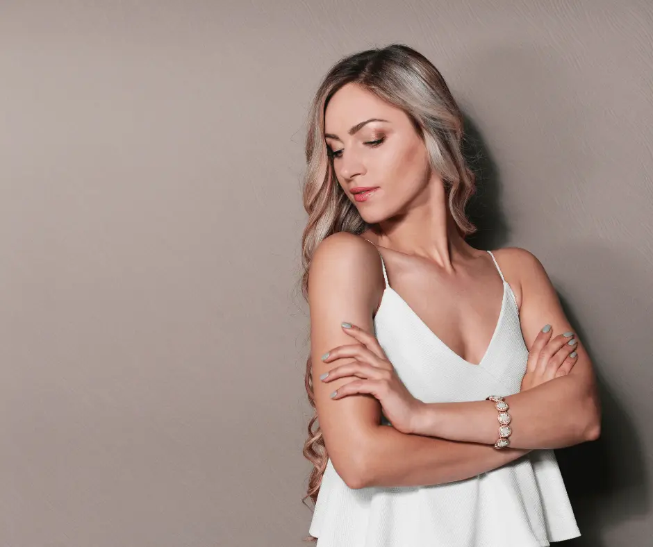 A woman in a white top showcasing her confident pose with her arms crossed.