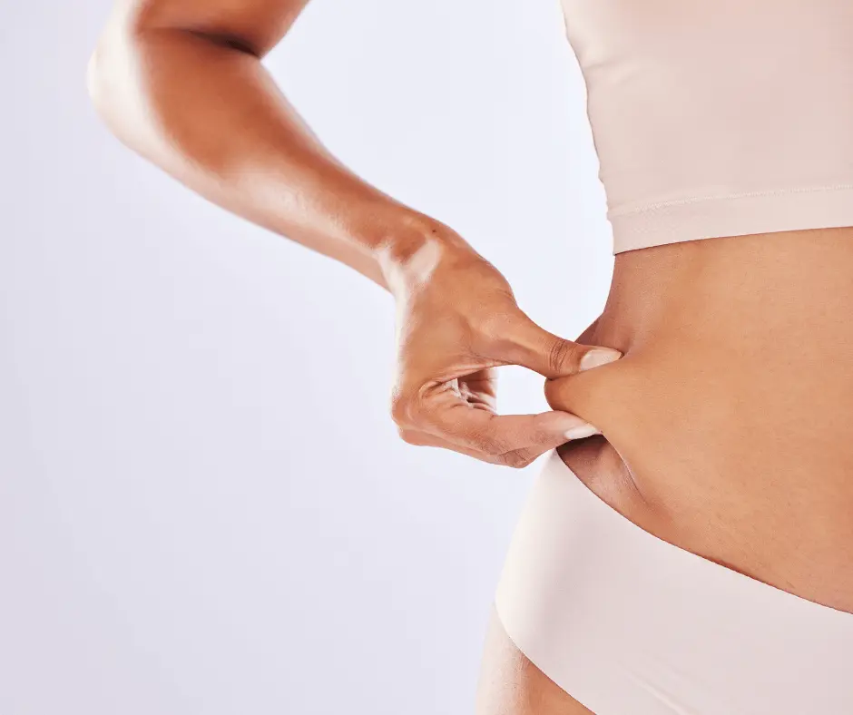A woman is putting her hand on her stomach after undergoing Smartlipo.