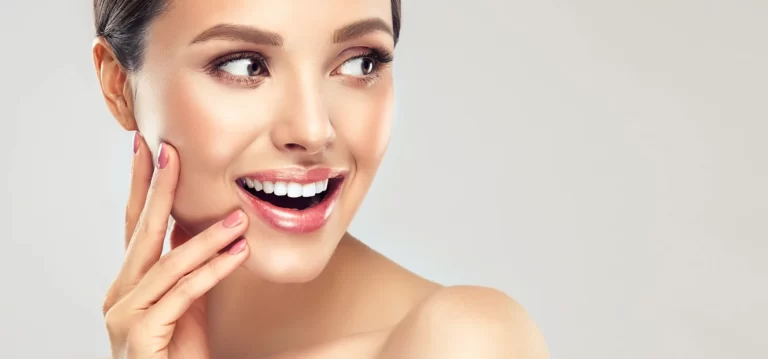 A woman with a beaming smile and her hands resting on her face, showcasing her happiness after smart lipo chin procedure.