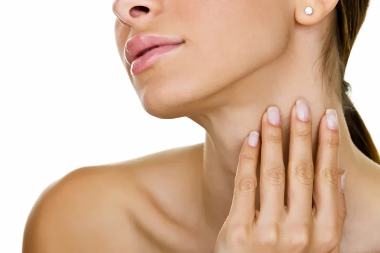 A woman is touching her neck with her hands, showcasing her defined jawline.
