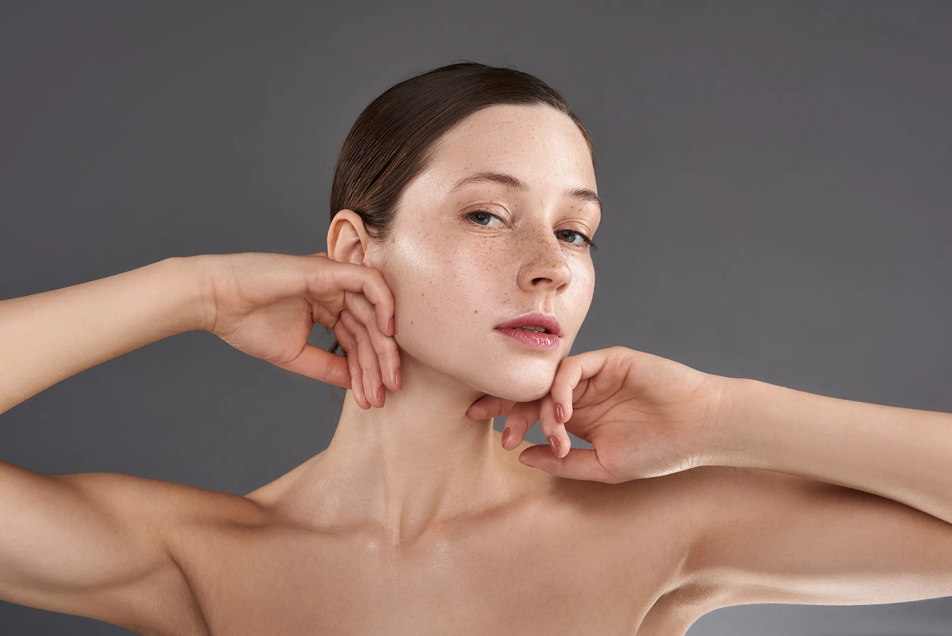 A woman is posing with her hands on her face, showcasing her aesthetic transformation after Victoria Paris Chin Lipo.