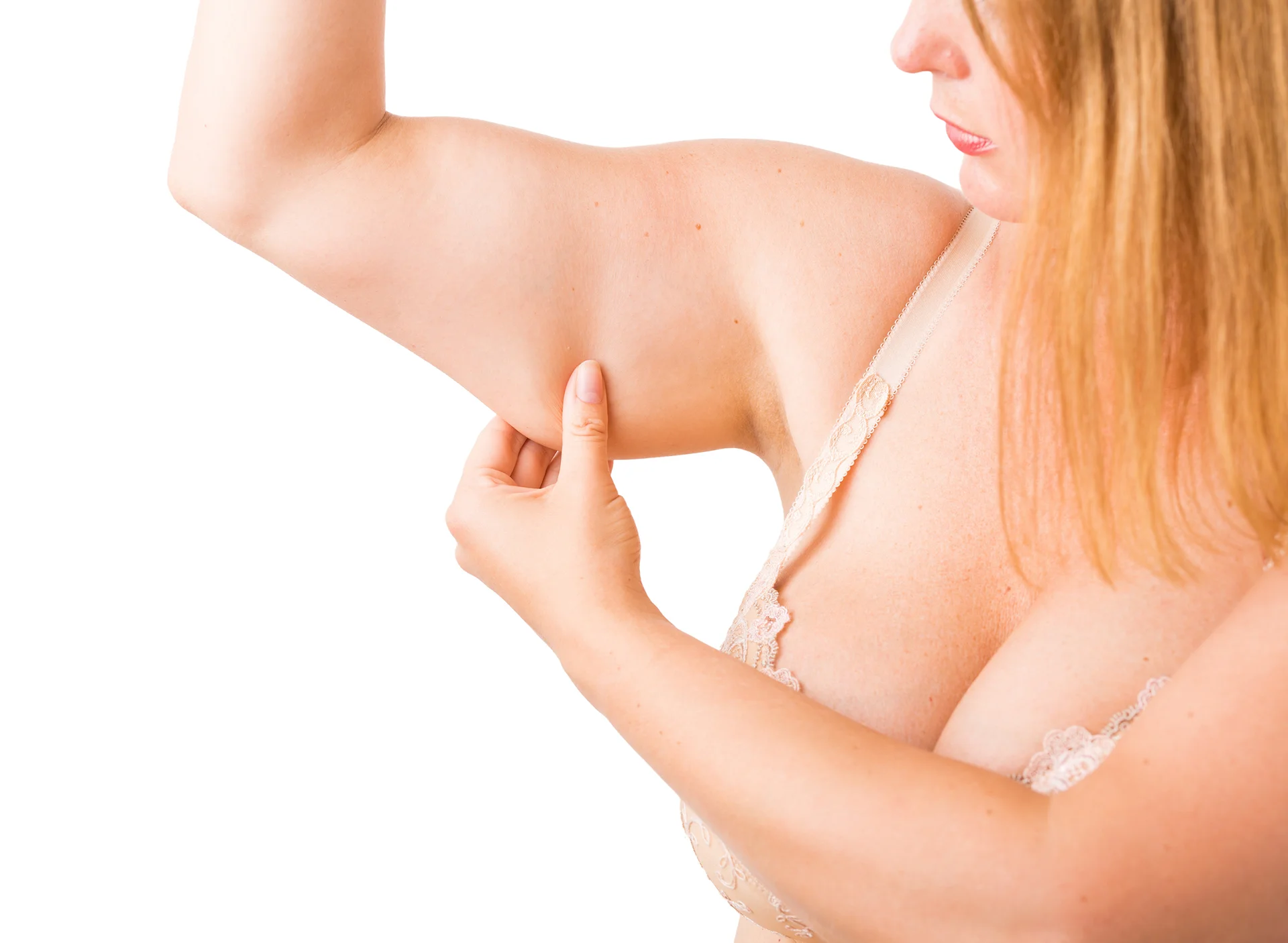 A woman pinching the skin on her upper arm, examining it closely as part of an arm liposuction procedure consultation, isolated on a white background.