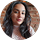A woman with long dark hair and light skin is smiling slightly, wearing a light top, with a blurred brick wall background—perfect for showcasing client testimonials or positive reviews.